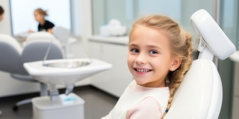 Junges Mädchen sitzt lachend im Zahnarztstuhl