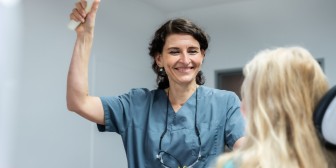 Dr. Jarry lächelt einer Patientin auf dem Behandlungsstuhl zu